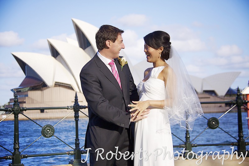 Couple laughing with hand on pregnant belly in front of Sydney Opera House - wedding photography sydney